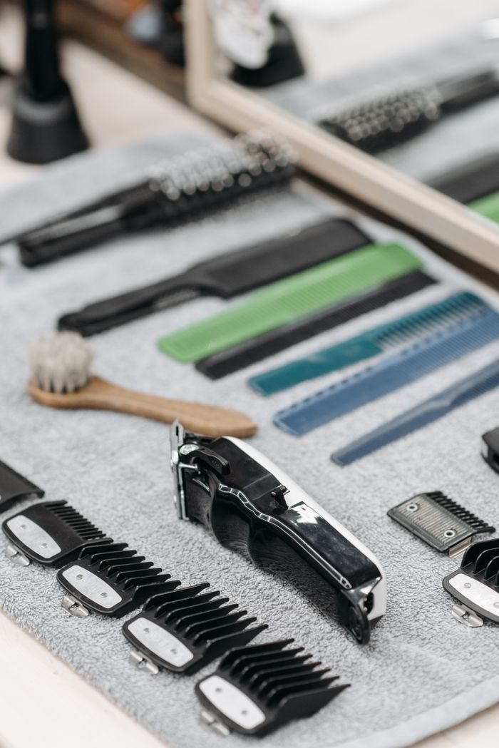 Close-up of various barber tools neatly organized on a towel, including clippers and combs.
